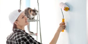 Girl painter, designer and worker paints a roller and brush the wall